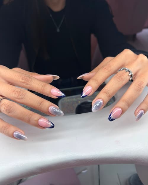Uñas esculpidas almendradas con francés azul noche y destellos plateados